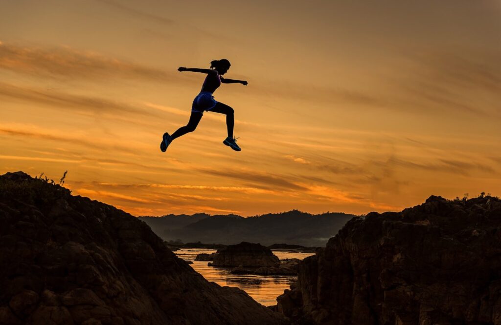 woman jumping between cliffs